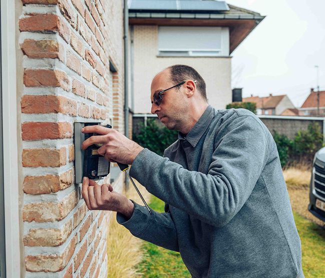 Kristof Devalckenaere voert een vakkundige installatie uit van een videofoniesysteem bij Kinderdagverblijf P'tit Doudous in Roeselare, ter bevordering van de veiligheid en toegangscontrole.