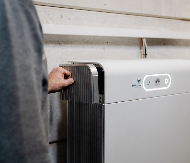 Installateur Kristof Devalckenaere bij een witte Huawei thuisbatterij (LUNA2000) voor slimme energieopslag, vakkundig geïnstalleerd met focus op kwaliteit.