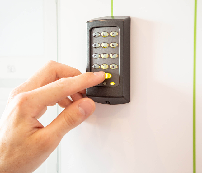 Een gebruiker voert een pincode in op een robuust codeklavier voor veilige toegangscontrole. Vakkundig geïnstalleerd door Devalckenaere Kristof voor een betrouwbare beveiliging van woning of bedrijf.